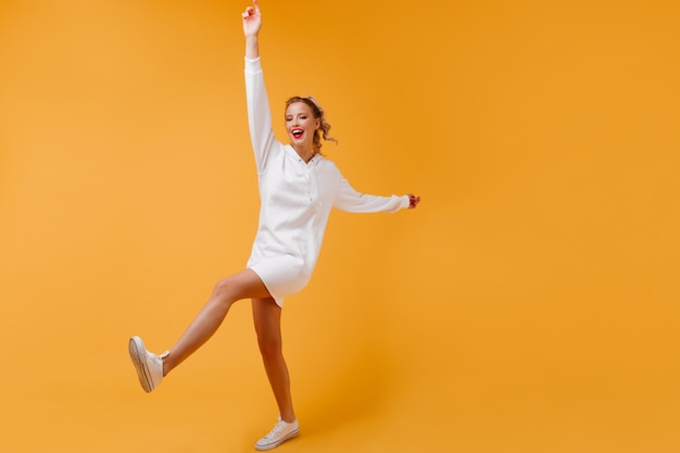 Active lady with slender legs moving in orange room
