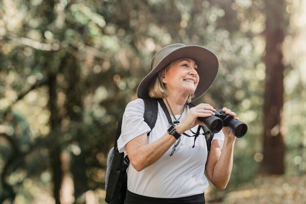 Активная старшая женщина с помощью бинокля, чтобы увидеть красоту природы