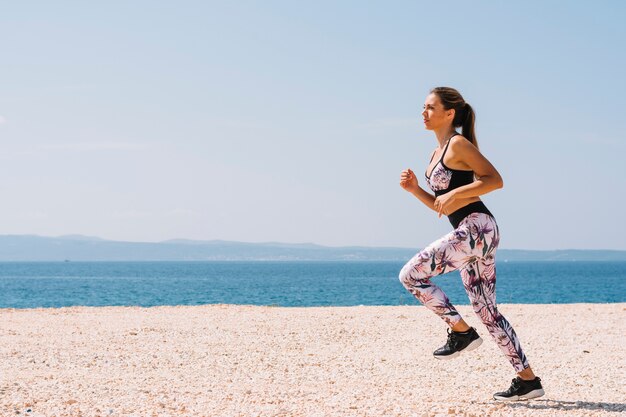 Active sporty young woman running along the ocean