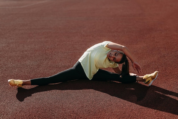 Бесплатное фото Активная женщина делает аэробные упражнения в позе шпагата