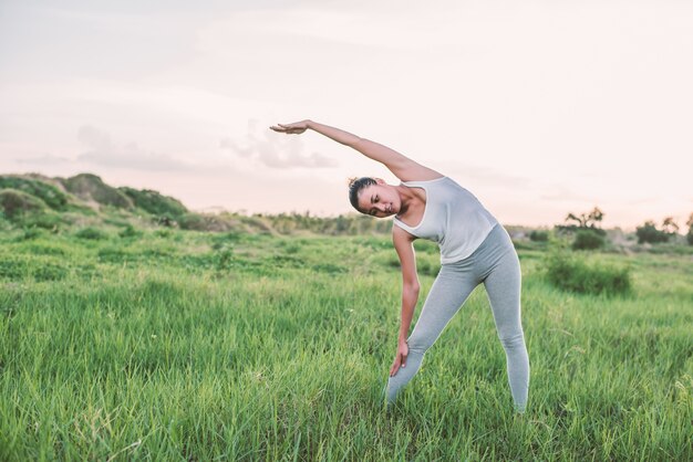 Active woman exercising in the meadow