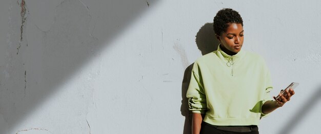 Active woman using a phone by a white wall