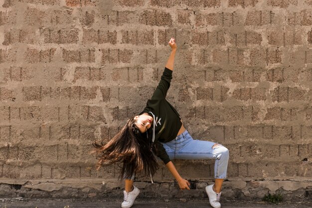 Активная молодая женщина, танцующая против старой стены