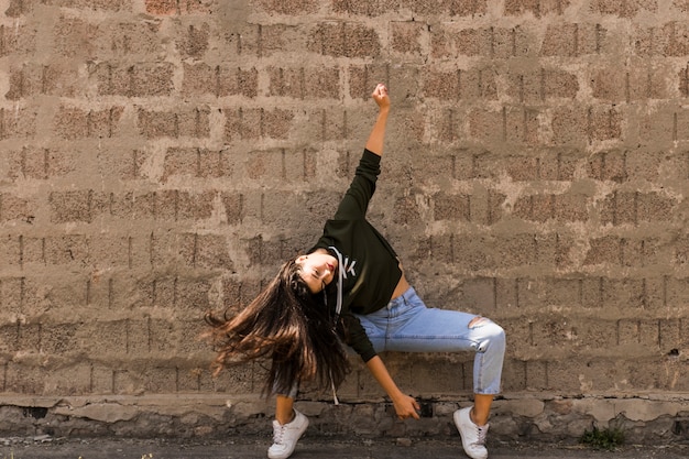 Active young woman dancing against old wall
