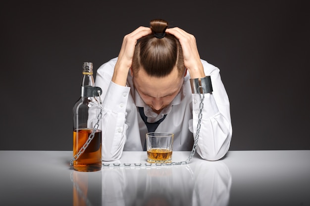 Addicted man looking at his glass of whiskey