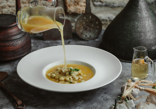 Adding broth to chicken soup with yellow beans.