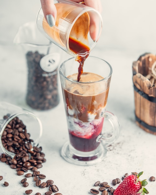 Adding espresso into coffee drink in a glass.