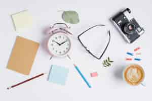 Free photo adhesive notes; pencils; rubber; eyeglasses; camera and cappuccino cup with latte art on white background