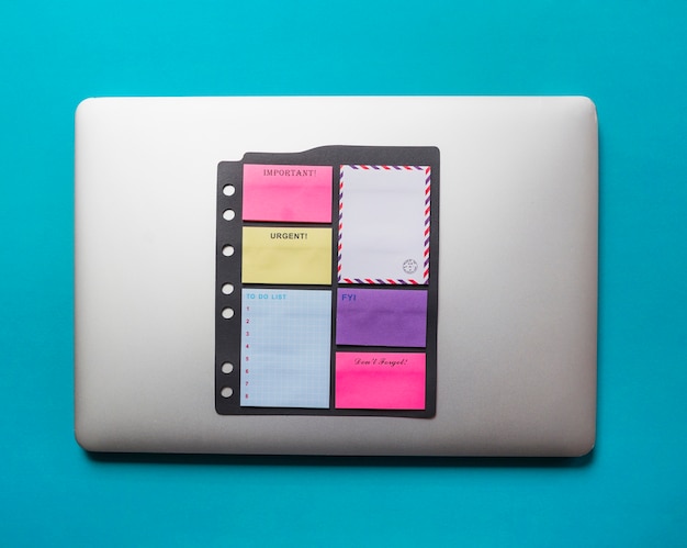 Free photo adhesive notes with envelope stucked on laptop against blue background