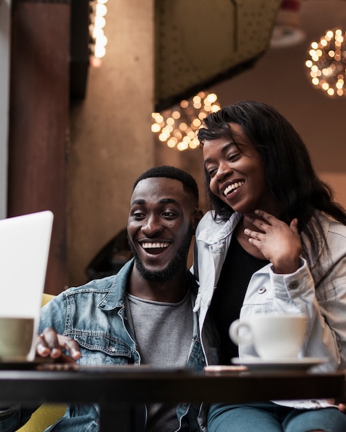 Adorable afroamerican couple looking at laptop