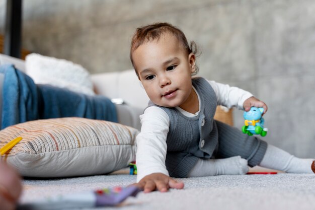 Очаровательный малыш ползает и играет на полу с игрушкой