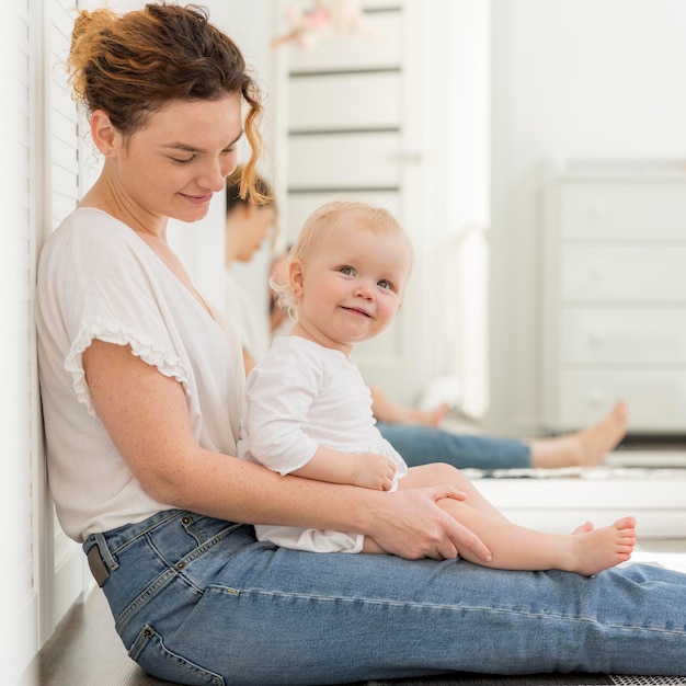 Adorable baby girl with mother at home