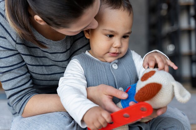 Adorable baby playing with his mother with toy