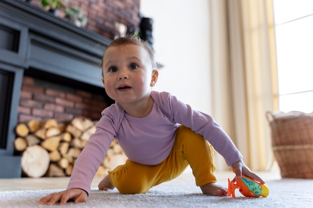Очаровательный ребенок играет с игрушкой дома на полу