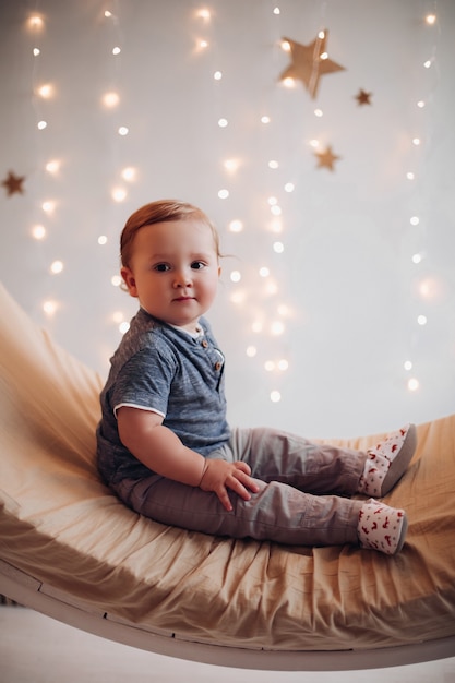 Adorable baby sitting on beautiful swing decorated for Christmas.