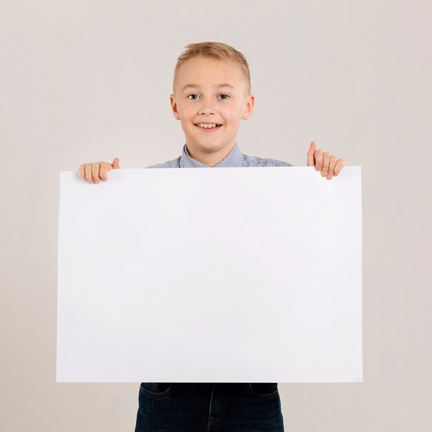 Adorable boy holding blank paper
