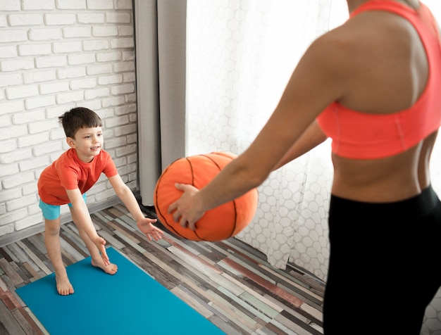 Foto gratuita addestramento adorabile del ragazzo con la madre a casa