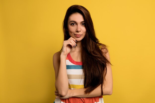 Adorable charming woman with long brown hair wearing summer brightful dress posing with adorable smile.