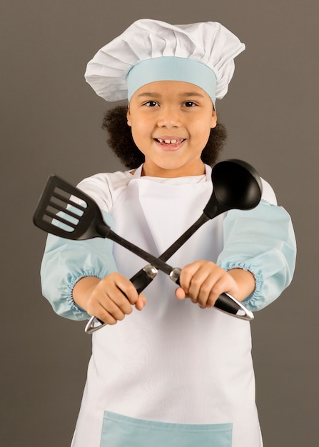 Adorable chef holding cooking utensils