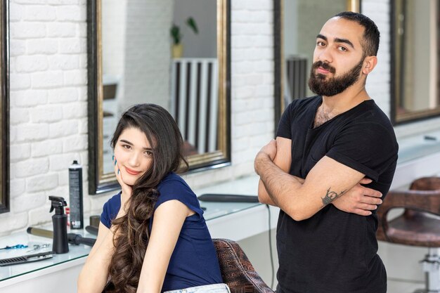 Adorable client sittin on a chair and barber crossed her arms and looking at the camera High quality photo