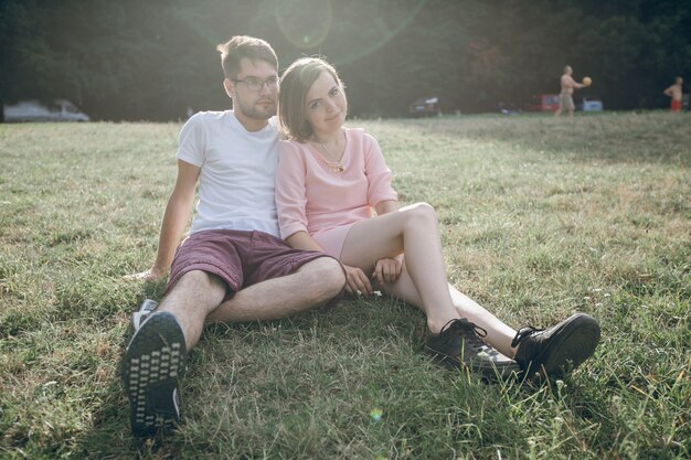 Adorable couple sitting together on the lawn of a park