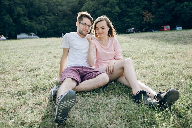 Adorable couple sitting together on the lawn of a park