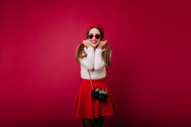 Adorable dark-haired lady expressing happiness during indoor photoshoot