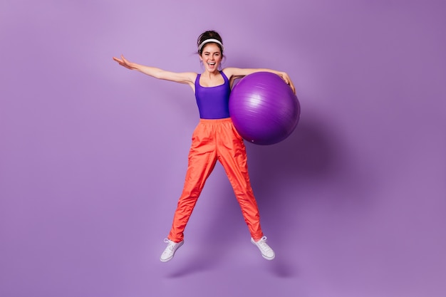 Adorable dark-haired woman in bright sports outfit doing exercises