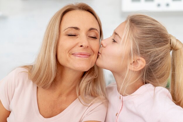 Adorable daughter kisses  her mother on cheek