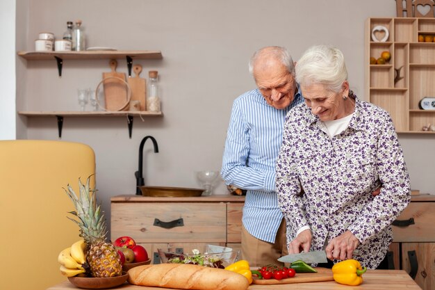 Adorable elderly couple cutting vegetables