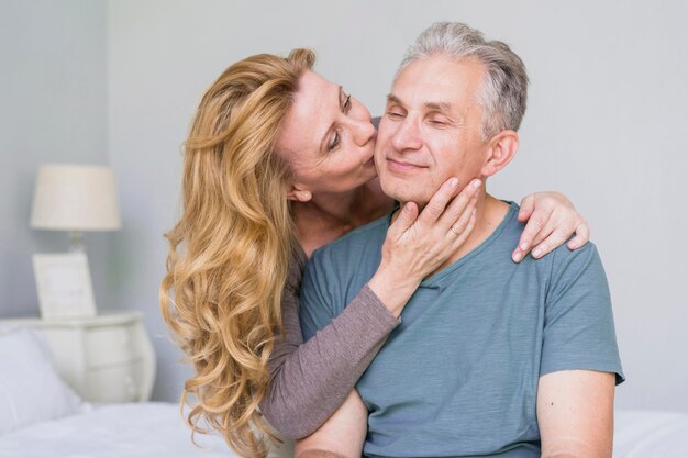 Adorable elderly woman kissing her husband