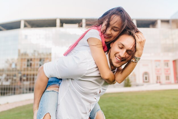 Adorable female model embracing husband sitting on his back