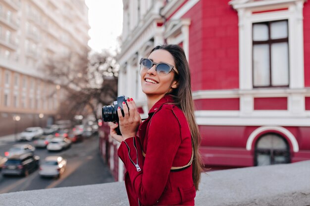 Adorable female model taking picture of city with camera