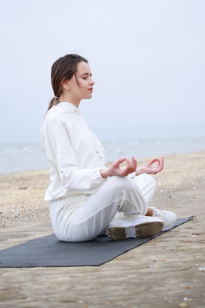 Очаровательная девушка занимается медитацией на пляже Фото высокого качества