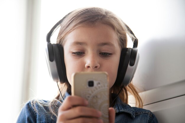 Adorable girl in headphones browsing smartphone