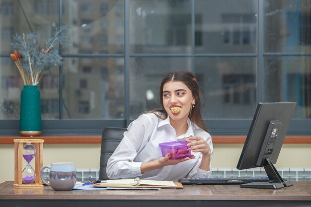 彼女の口でクッキーを保持し、脇を見て愛らしい女の子