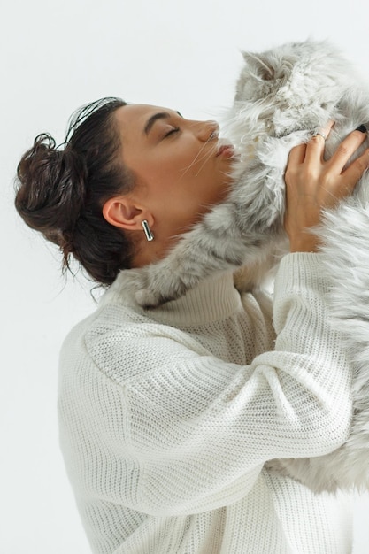 The adorable girl hugged her cat and sit on white background High quality photo