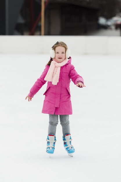 Foto gratuita vista frontale di pattinaggio su ghiaccio della ragazza adorabile