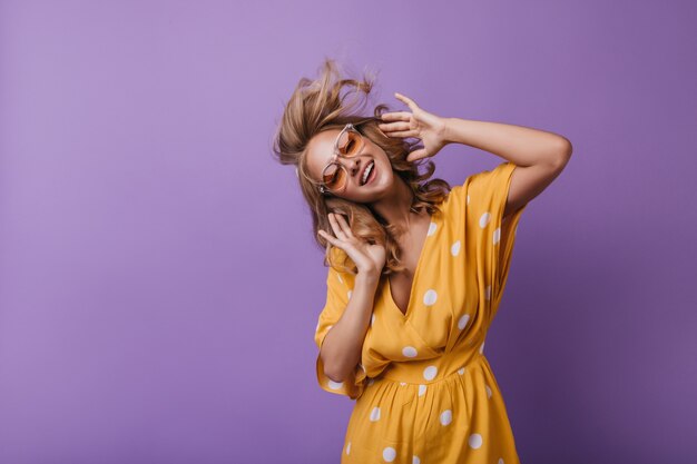 Adorable girl in orange attire dancing while listening music. blonde woman enjoying favorite song.