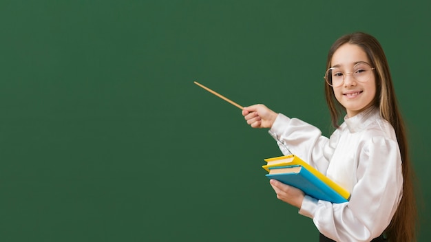 Adorable girl pointing at blackboard