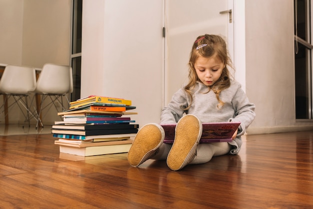 Free photo adorable girl reading books on floor