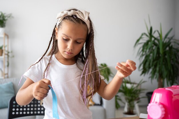 Adorable girl sewing clothes by hand