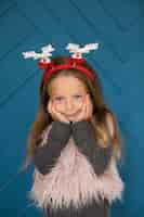 Free photo adorable girl sitting next to blue wall