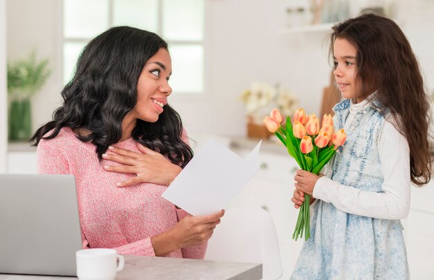 Adorable girl surprising mom with flowers