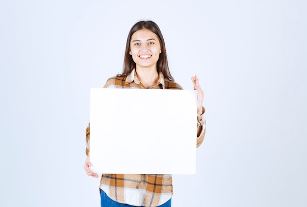  adorable girl with white big blank posing over white wall. 