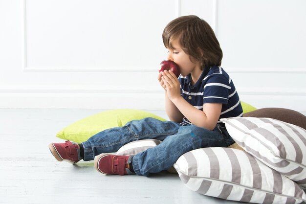 Adorable kid on the floor eating apple