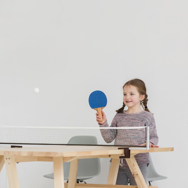 Adorable kid playing ping pong indoors