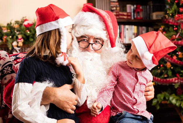 Adorable kids sitting on a santa legs on christmas