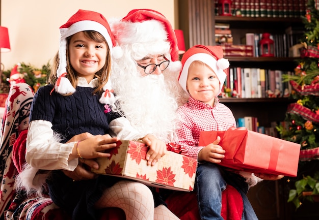 Adorable kids sitting on a santa legs on christmas