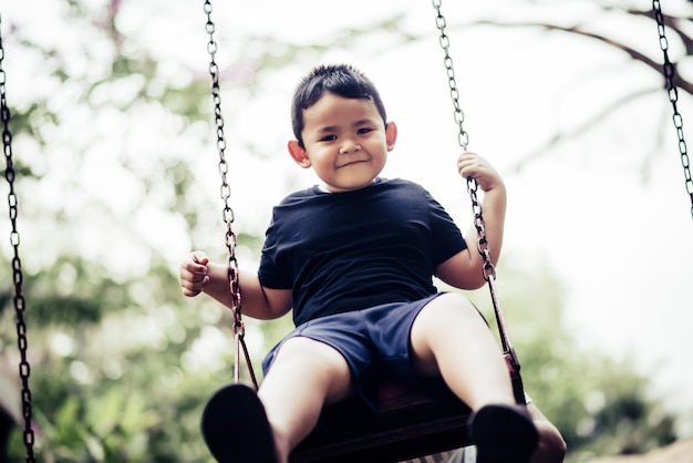 Adorable little boy having fun on a swing outdoor